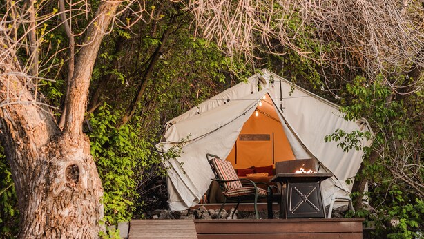 A tent with a table and chairs set up in a forested area, connected to a wooden deck. - Glamping | Outdoor Shower | Bathroom (Providence)