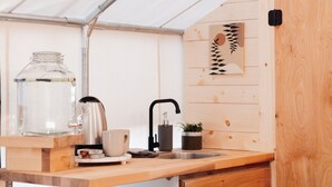 A kitchen with a wooden countertop, a coffee maker, a kettle, a sink, and a small potted plant. - Glamping | Outdoor Shower | Bathroom (Providence)