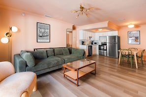 Uma sala de estar com sofá, mesa de centro e um espaço de refeições com cadeiras.