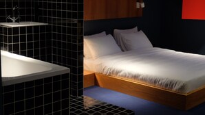 A modern bedroom with a wooden bed, white bedding, and a black-tiled sink area. - Cosy and Stylish (T'bilisi)