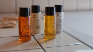 Four bottles of shampoo on a tiled surface. - Cosy and Stylish (T'bilisi)