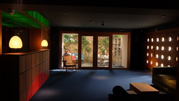 A modern interior with a seating area, a wooden cabinet, and a wall with circular lights. - Cosy and Stylish (T'bilisi)
