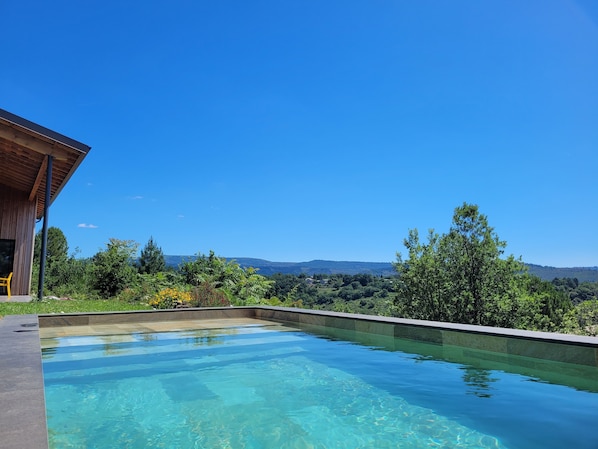 A clear swimming pool with a view of a mountainous landscape.