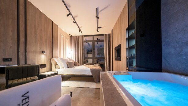 A modern bedroom with a large bed, a sitting area, and a heated bathtub. - Velvet rooms & more (Zadar)