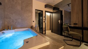 A modern bathroom with a large bathtub, a chair, and a wooden vanity. - Velvet rooms & more (Zadar)