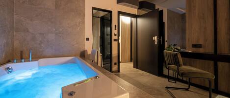 A modern bathroom with a large bathtub, a chair, and a wooden vanity.