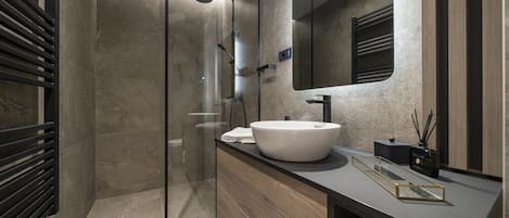 A modern bathroom with a glass-enclosed shower, a large mirror, and a wooden vanity.