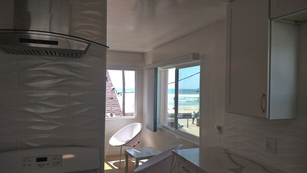 A room with a view of the ocean, a ceiling fan, a window, and a chair. - Studio #1 Fully-equipped with Boardwalk Patio Access - Oceanfront! Pet-Friendly! (San Diego)