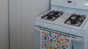 A kitchen with a white stove, a white oven, and a white cabinet with two doors. - Studio #1 Fully-equipped with Boardwalk Patio Access - Oceanfront! Pet-Friendly! (San Diego)
