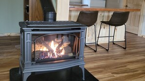 Ein Holzofen in einer Küche mit Holzboden, zwei Stühlen und einem Kühlschrank.