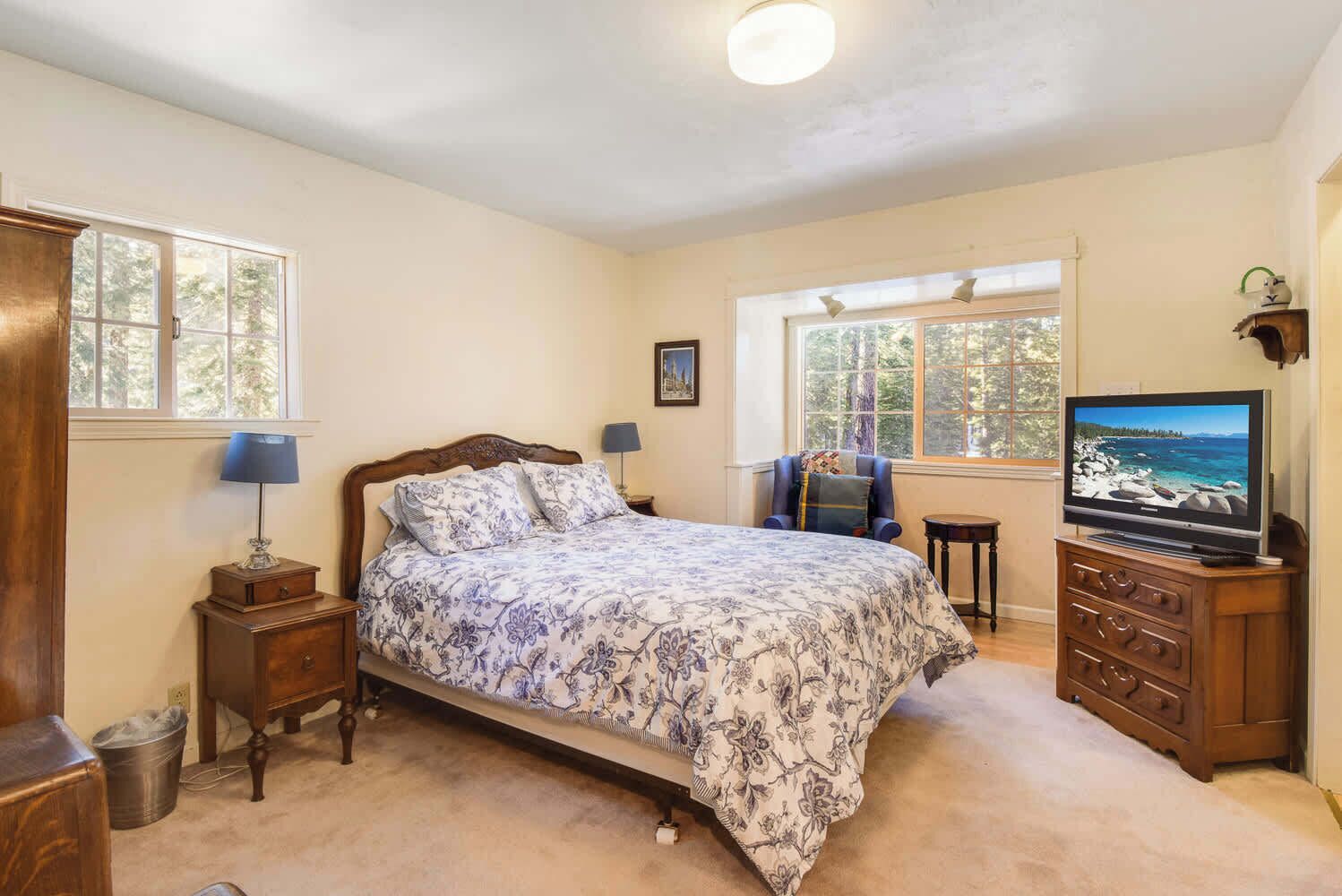 A bedroom with a bed, a television, a chair, and a dresser.