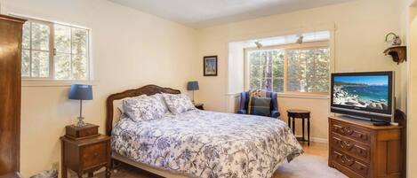 A bedroom with a bed, a television, a chair, and a dresser.