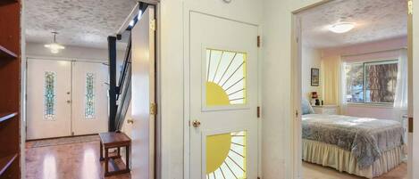 A hallway with a wooden bench, a staircase, and a door with a sunburst design.