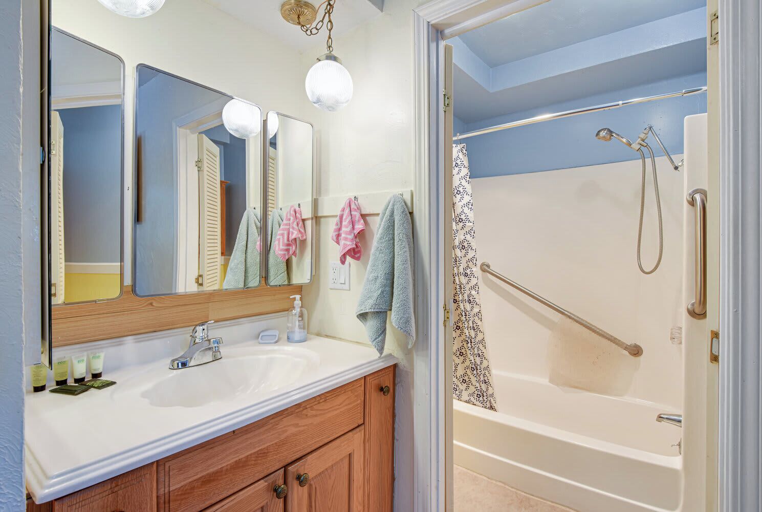 A bathroom with a sink, mirror, and shower.