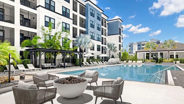 A modern pool area with lounge chairs, a fire pit, and a covered seating area. - Landing Tampa Westshore (Tampa)