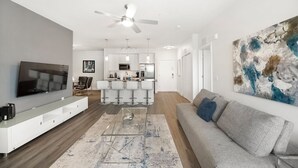 A modern living room with a flat-screen TV, a sofa, a coffee table, and a bar area with stools. - Landing Tampa Westshore (Tampa)