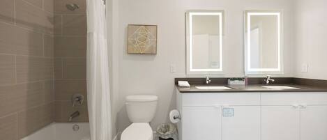Een moderne badkamer met douche, toilet en wastafel met twee spiegels.