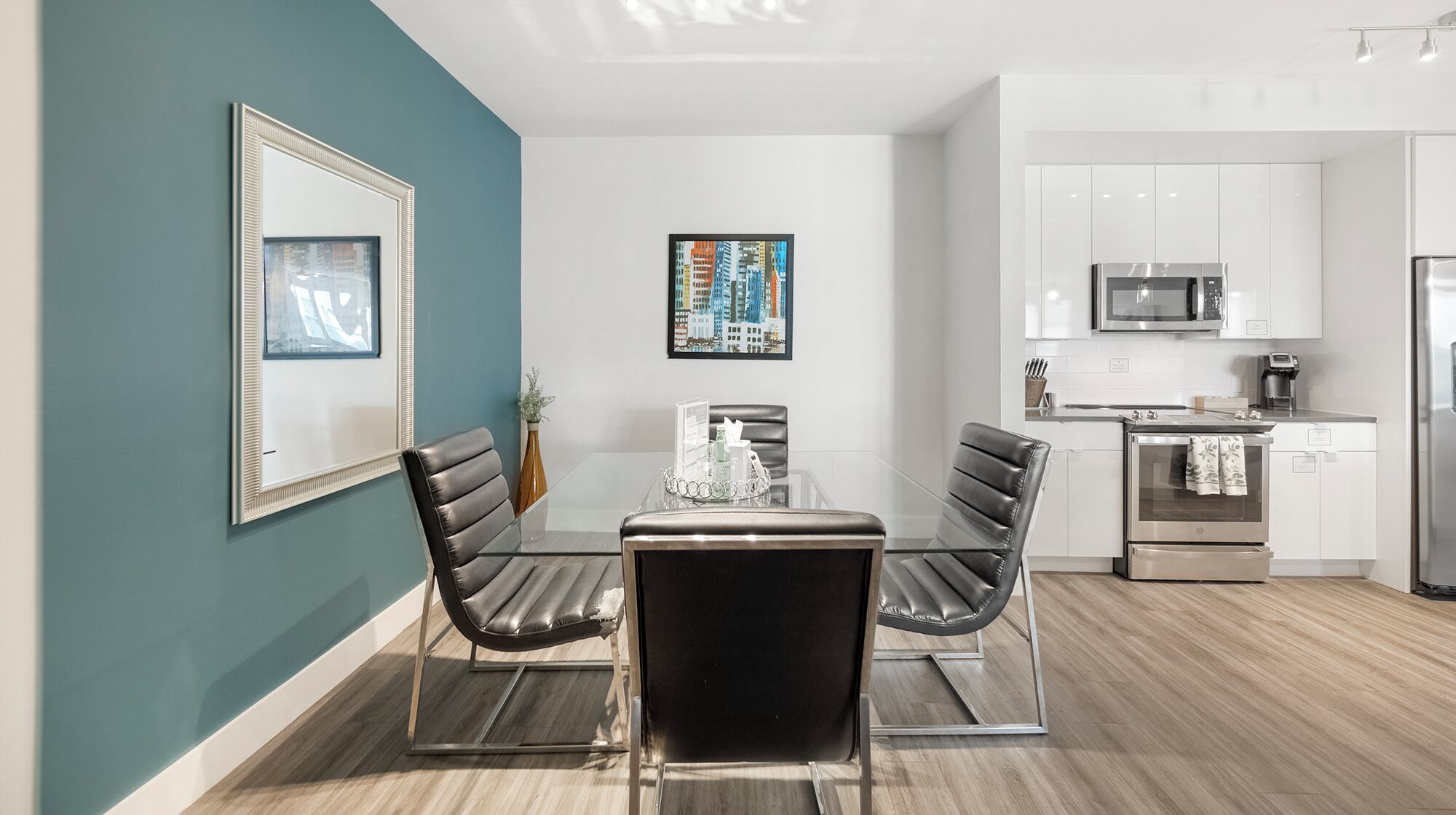 A modern kitchen with white cabinets, a stainless steel refrigerator, and a microwave.