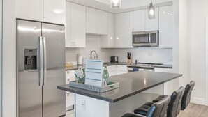 A modern kitchen with stainless steel appliances, a central island, and bar seating. - Landing Tampa Westshore (Tampa)