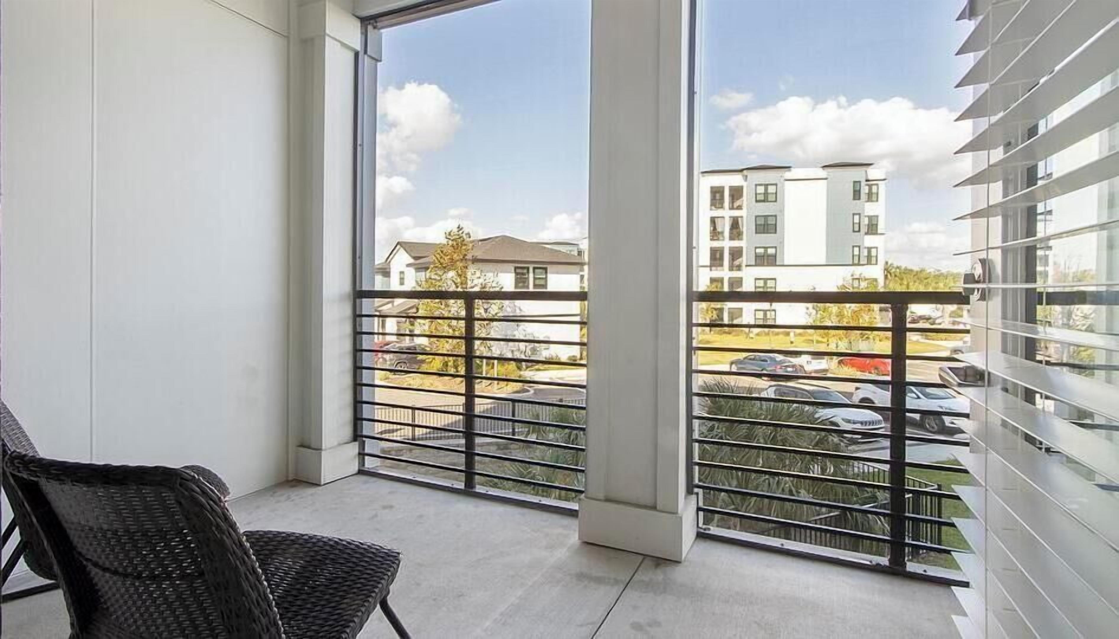 A balcony with a view of a parking lot and buildings.