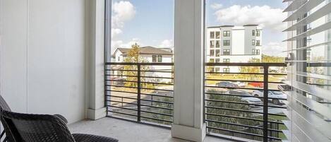 A balcony with a view of a parking lot and buildings.