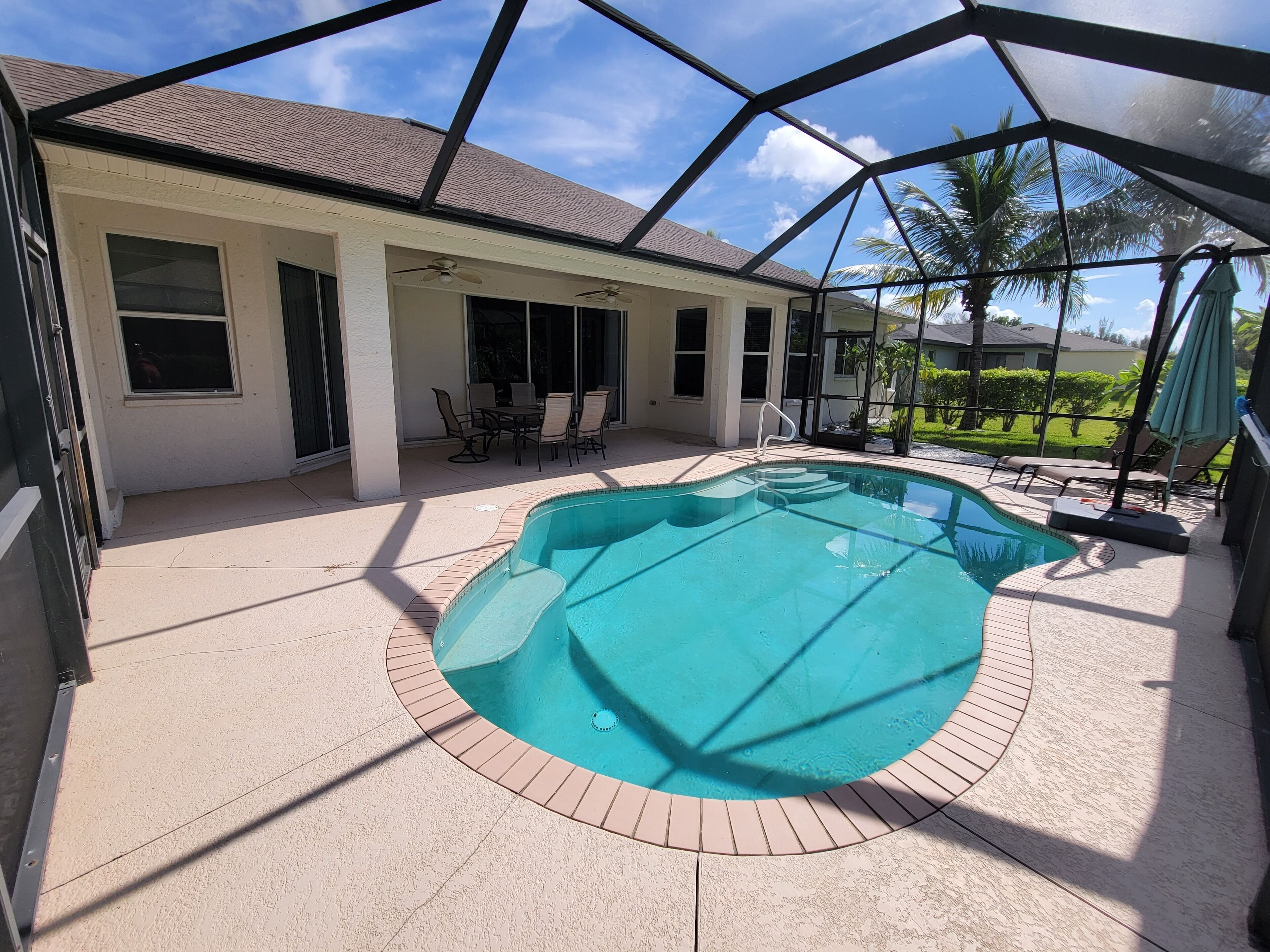 A covered swimming pool with a patio area, a covered seating area, and a view of the surrounding landscape.