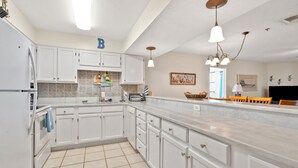 A spacious kitchen with white cabinets, a large island, and a tiled floor. - Escape to the ultimate beach retreat (North Myrtle Beach)