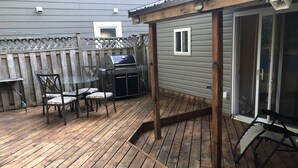 Una terrassa de fusta amb una barbacoa i cadires.