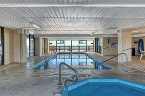 An indoor swimming pool with a view of a building outside, a lifeguard sign, and a no lifeguard on duty sign. - Atalaya Tower 1505 - Three Bedroom, Oceanfront Condo in Garden City Beach (Garden City Beach)