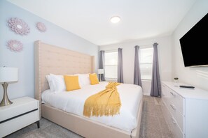 Un dormitorio ordenado con cama, mesita de noche, cómoda y televisión de pantalla plana.
