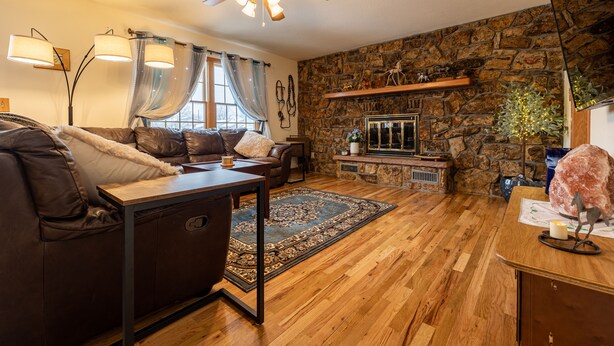 Ein gemütliches Wohnzimmer mit Kamin aus Stein, einer Ledersofa und Holzböden.