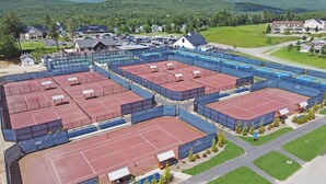 A large sports complex with multiple tennis courts, surrounded by residential buildings and a mountainous backdrop. - Beautiful resort condo with golf course views (Thornton)
