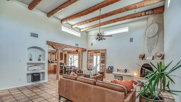 A spacious living area with a brown sofa, a ceiling fan, and a large window.