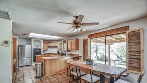 A kitchen with wooden cabinets, a stainless steel refrigerator, a microwave, and a ceiling fan.