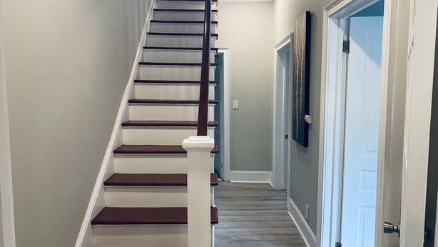 A staircase with wooden steps and white railings leading to a landing. - Historic Pursuit of Happyness (Gastonia)