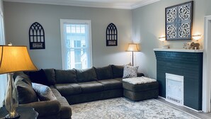 A living room with a sectional sofa, a patterned rug, a fireplace, and decorative wall art. - Historic Pursuit of Happyness (Gastonia)
