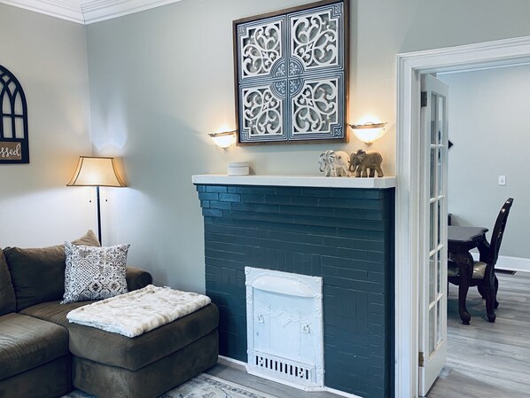 Una sala de estar con chimenea, un sofá, una lámpara y decoración en la pared.