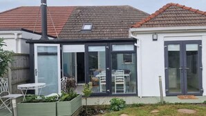 Una casa con puerta de cristal que da a un patio con mesa y sillas.