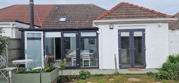 A house with a glass door leading to a patio area with a table and chairs. - Beach house 200m to beach.Stylish, Modern Sleeps 6. Suit Summer or Winter break (mablethorpe)