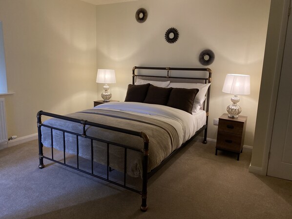A neatly made bed with a metal frame, two bedside tables with lamps, and decorative wall plates.