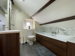 A modern bathroom with a toilet, a bathtub, and a vanity.