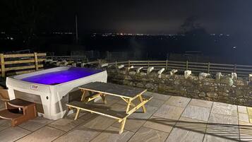 Relax in the hot tub surrounded by a city view, with a bench and table nearby.