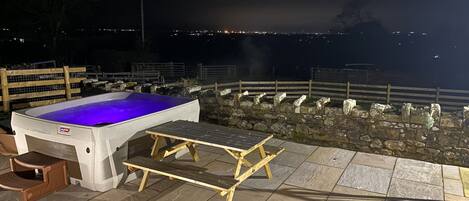An outdoor hot tub area with a stone wall and a wooden deck.