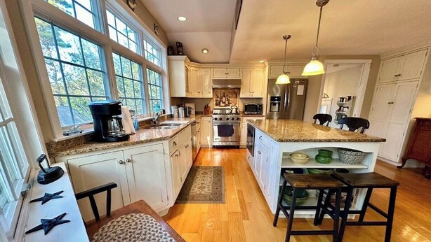 A spacious kitchen with a large island, wooden countertops, and a view through the windows.