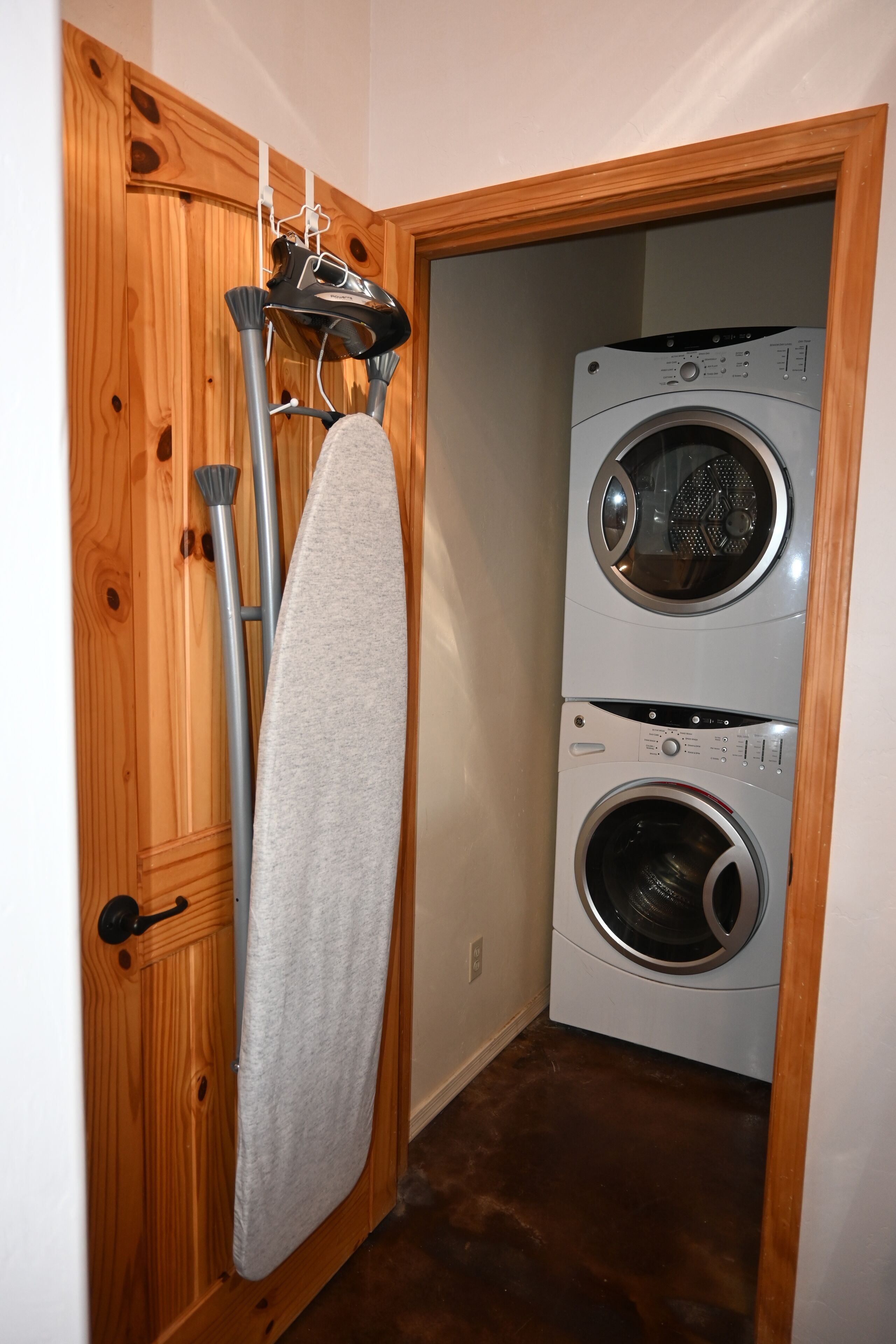 A laundry room with two stacked front-loading washing machines and a drying rack with a towel.