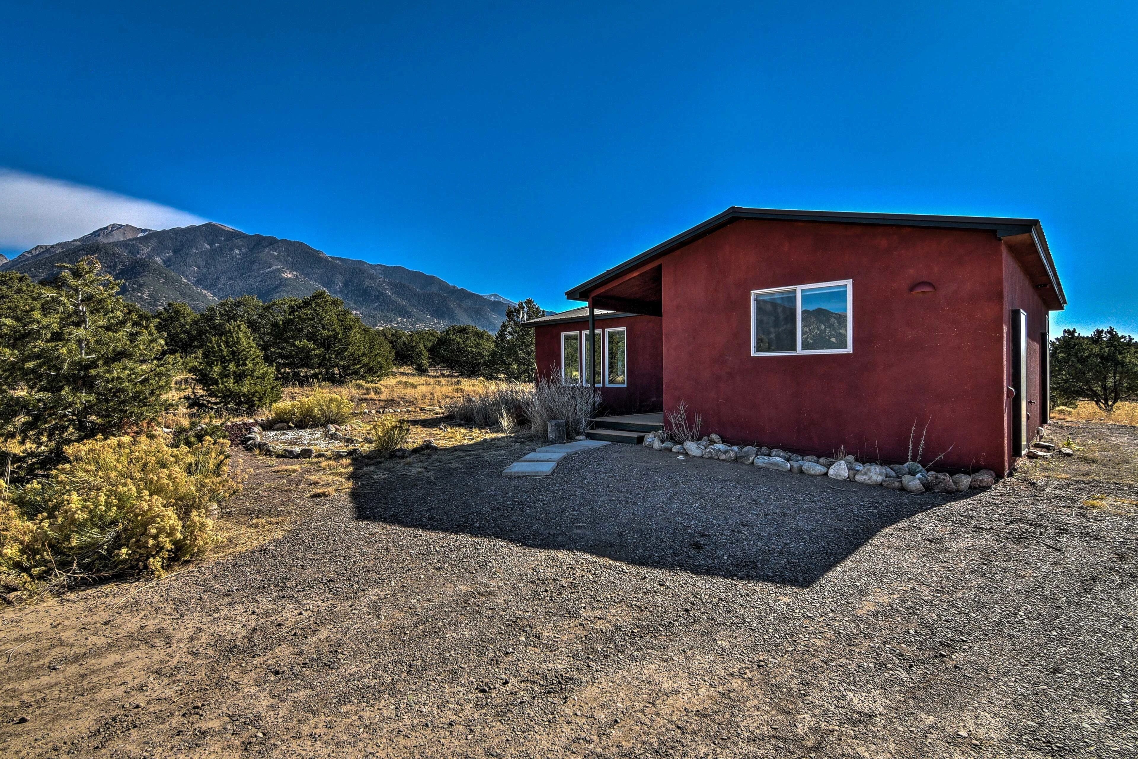 A red building with a gravel driveway and a mountain in the background.