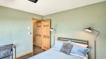 Une chambre à coucher comprenant un lit, des lampes de chevet, un bureau avec une chaise et une armoire en bois.