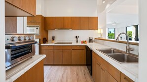 Una cucina moderna con mobili in legno, forno integrato, microonde e lavello.