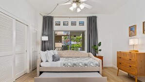 Una camera da letto con un letto, una cassettiera, una ventola a soffitto e vista sull'esterno.