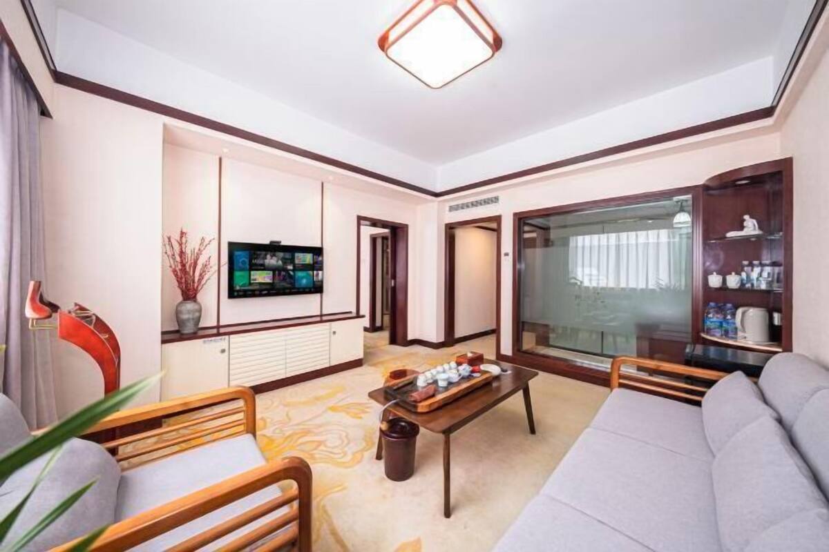 A modern living room with a sofa, a coffee table, a TV, and a glass cabinet.
